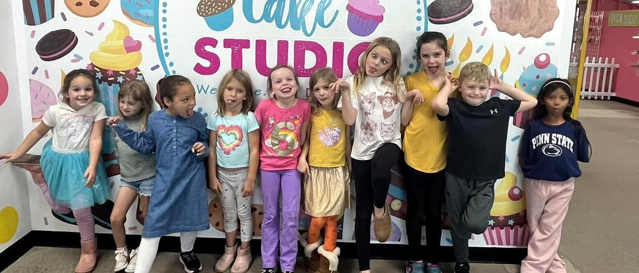 A row of party guests making silly faces in front of the Jubilee Cake Studio mural