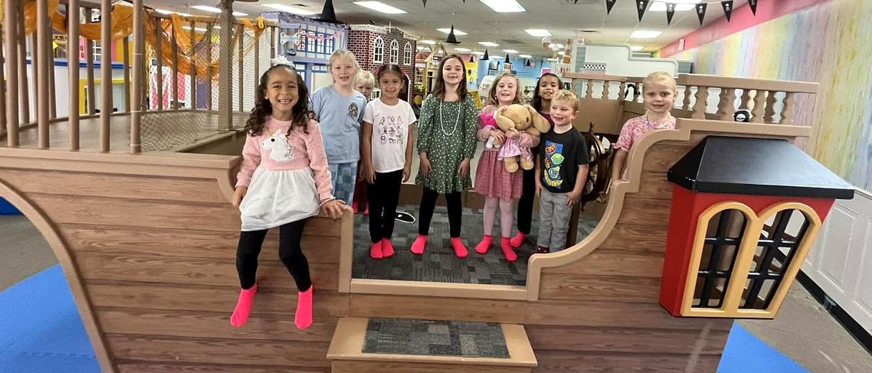 Smiling party guests in pink grippy socks aboard the play pirate ship