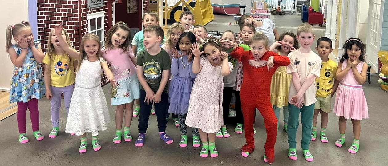 A birthday group in grippy socks making silly faces in front of the Mini Mansions firehouse