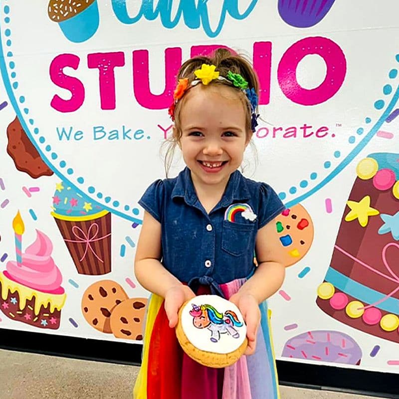 Girl proudly holding the unicorn cookie she painted