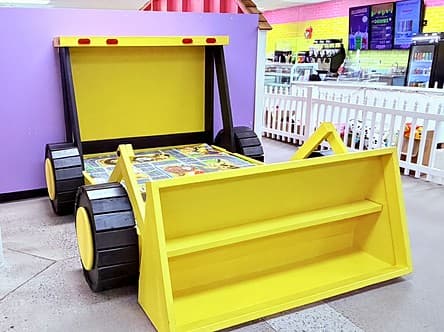 Big yellow bulldozer with a scoop out front and a play-road mat inside