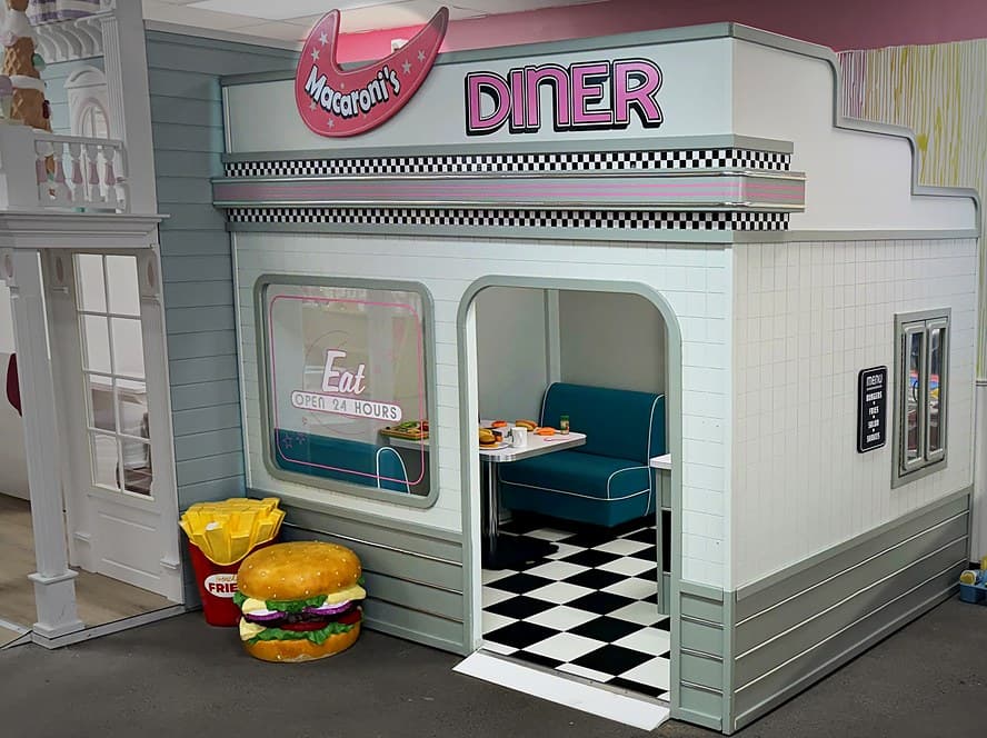 Macaroni's Diner playhouse with a teal booth, checkerboard floor and a giant burger and fries out front