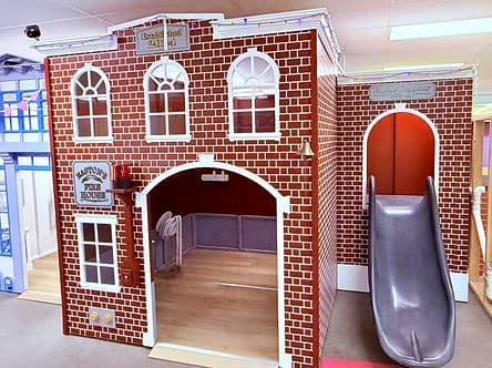 Easton's red-brick Fire House playhouse with arched windows and a silver slide