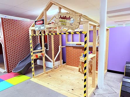 Jubilee's Hammer Time Construction Site, an open wood frame with caution tape, a danger sign and a kid-sized workbench