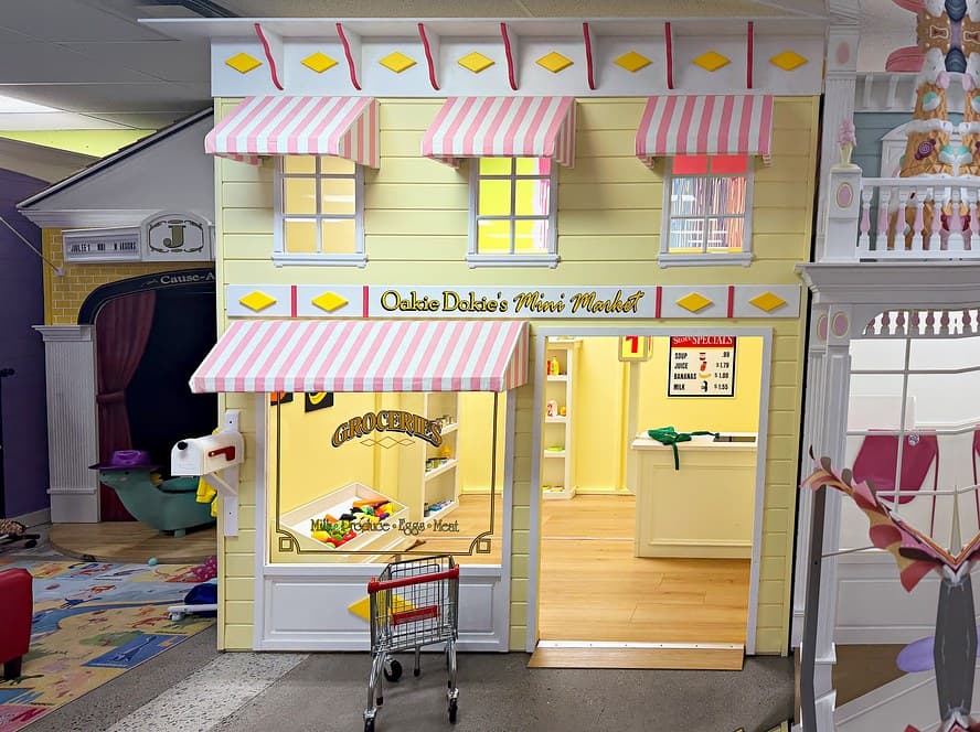 Oakie Dokie's Mini Market with pink-striped awnings and a tiny shopping cart at the door