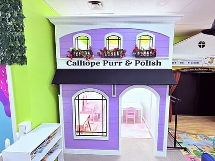 Calliope Purr & Polish salon, a lavender playhouse with flower boxes and a pink table and chairs inside
