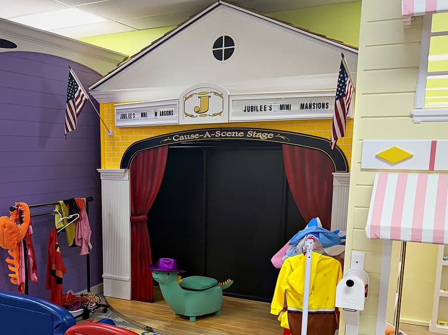 The Cause-A-Scene Stage with red curtains, flags and a rack of dress-up costumes